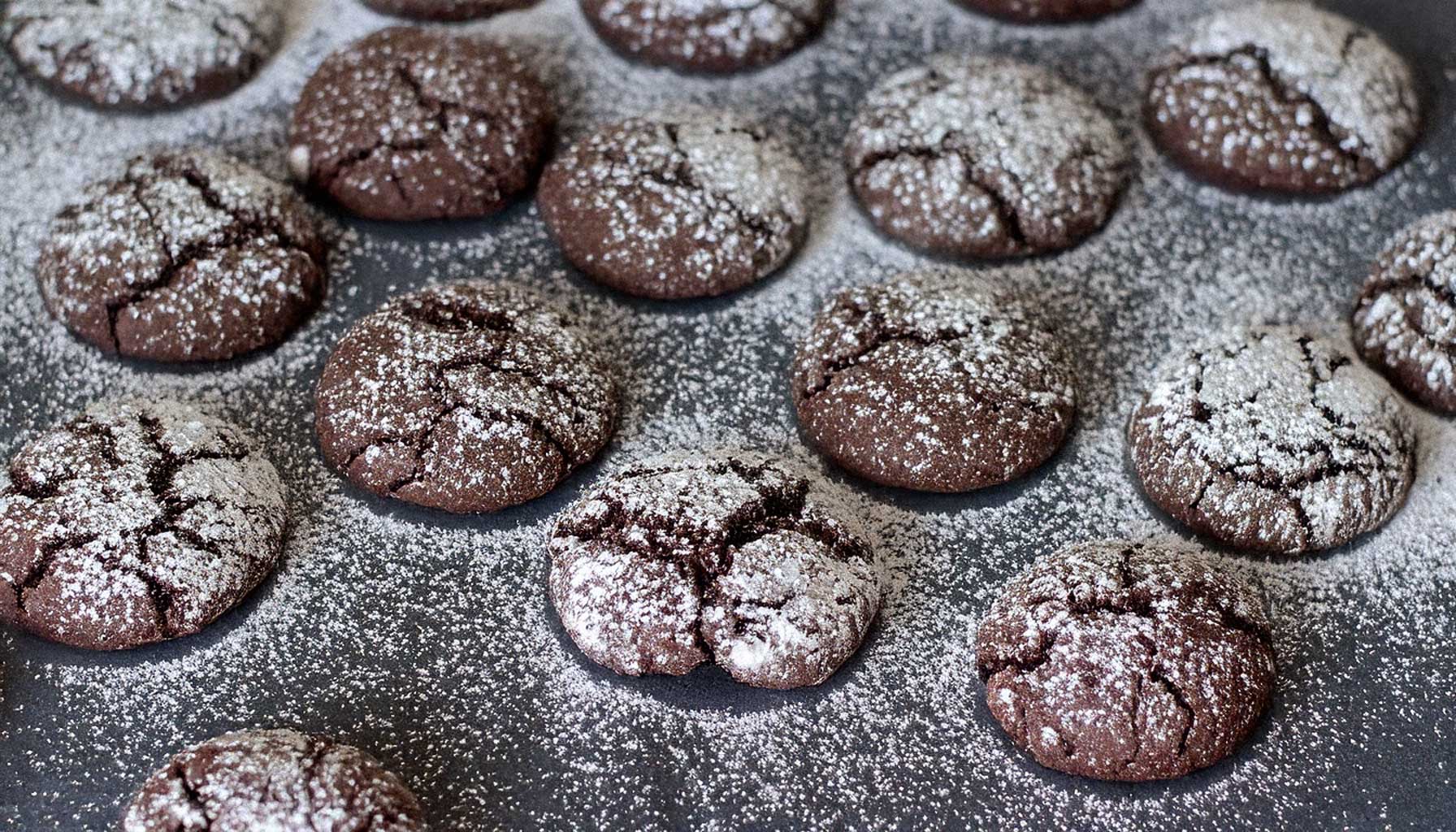 Frisch gebackene Schoko-Cookies mit einer knusprigen Puderzuckerschicht, die aufreißt.